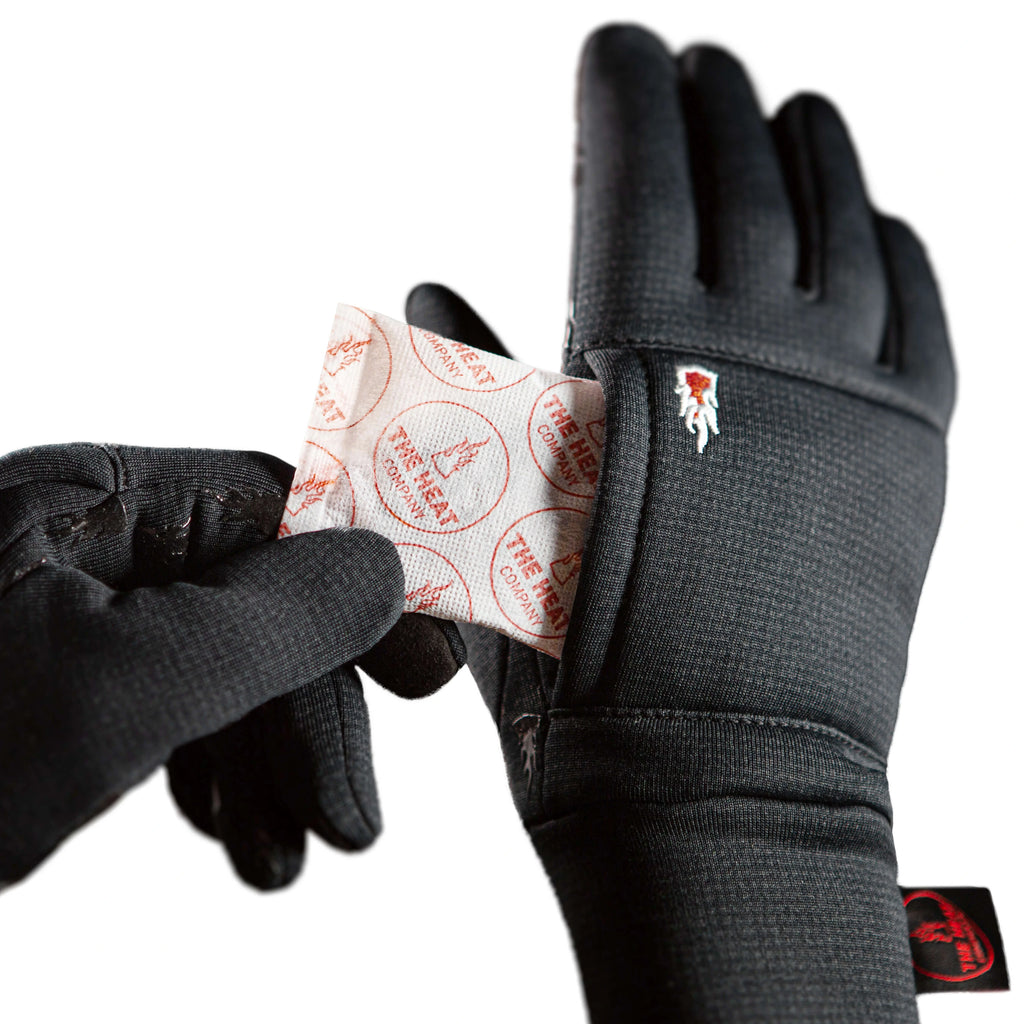 Closeup on a black gloves Windpro Liner with The Heat Company brand logo holding a small heat pack.