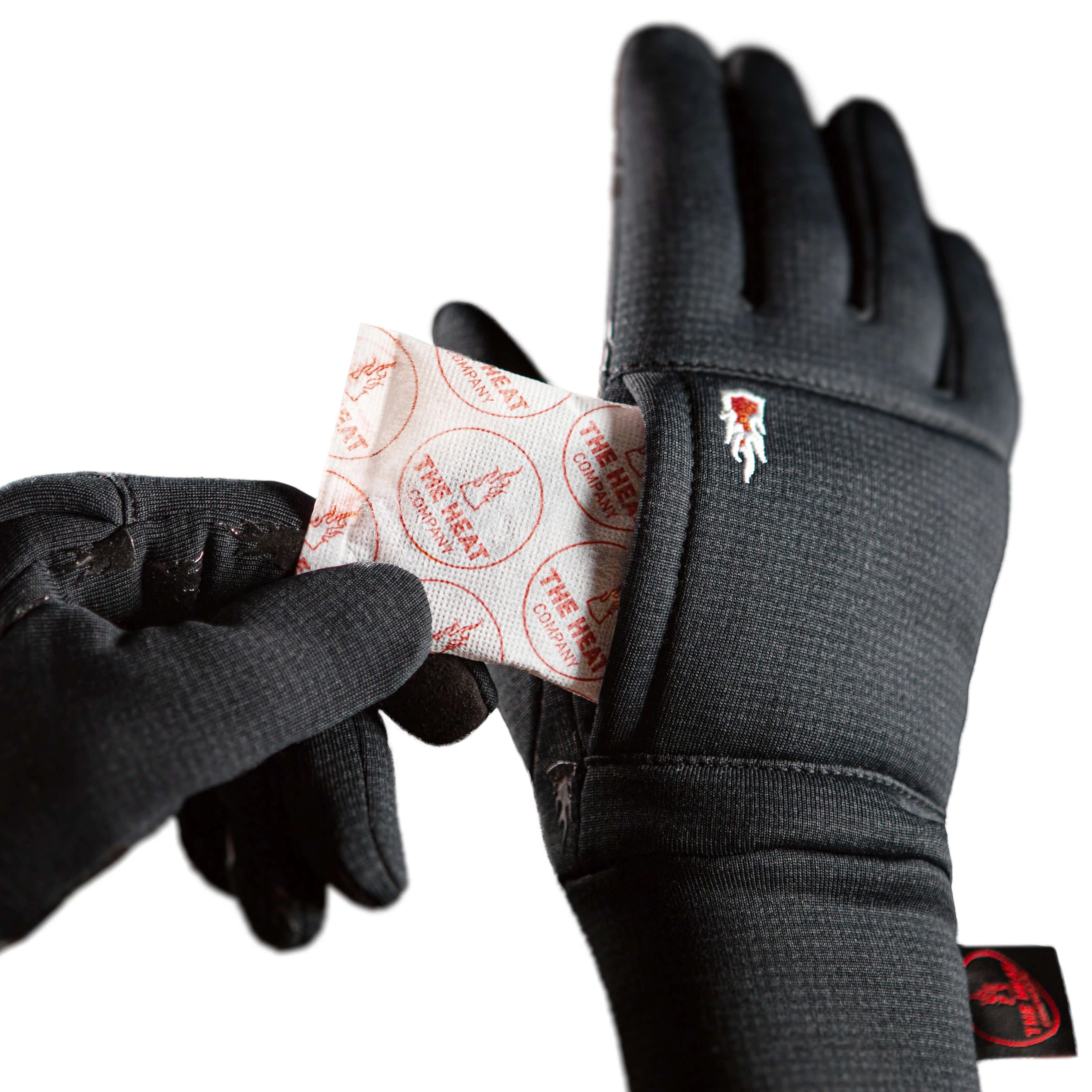Closeup on a black gloves Windpro Liner with The Heat Company brand logo holding a small heat pack.